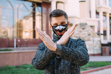 The guy wearing a black mask  with stylish pattern to protect against virus Covid-19 shows a hand gesture stop for stop coronavirus outbreak - 342416875
