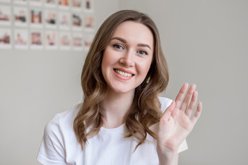 Portrait of smiling young woman sit on a couch look at camera, girl talks on video call, girl conducts a video chat dialogue