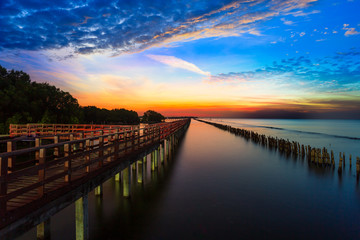 Obraz premium Bridge and sunset,Beautiful wooden red long bridge with sunset at samut sakhon province,Thailand is a dolphin view point called mutshanu shring