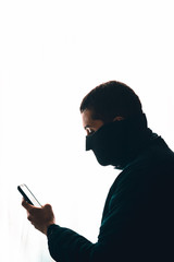 Retrato de un hombre con un cubre bocas revisando su teléfono celular.
