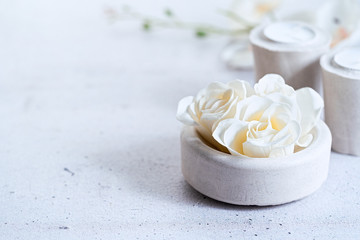 Composition with spa floral scented soap roses and cement gray candles over gray background, copy space. Selective focus. Wabi sabi, minimalism.