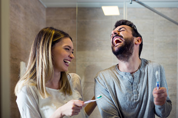 Fototapeta premium Happy couple washing teeth in morning, dental hygiene concept