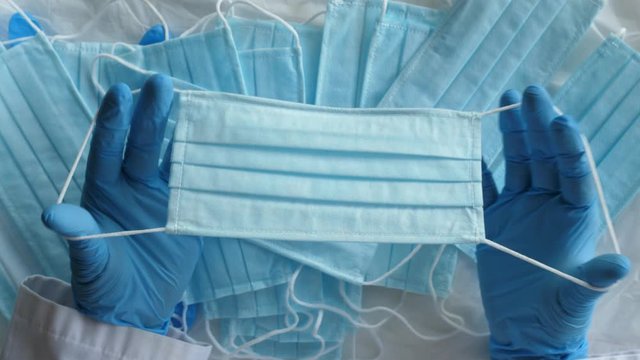 Doctor showing lot face mask holding equipment hands blue medical gloves