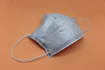 One protective white face mask to prevent fast spreading coronavirus on orange background, square.