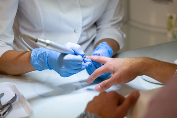 grinding and processing of nails in the salon close-up, master pedicure