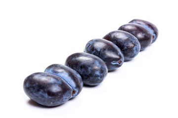 Fresh blue plums, isolated on white background, in close-up.