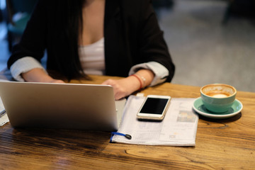 One woman using laptop computer. With a cup of coffee on wooden table. Blur background