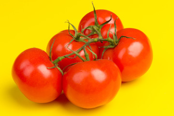 Cluster of the ripe red tomatoes on yellow  background