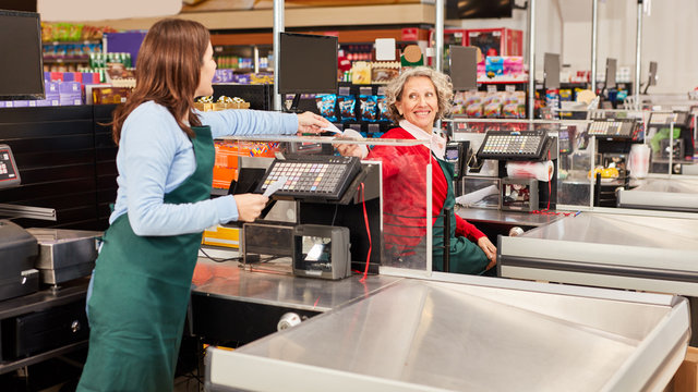 Two Women At The Supermarket Cashier As A Team