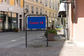 Schild vor einer Einkaufsstraße in der Innenstadt mit COVID-19