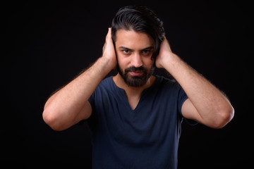 Portrait of handsome bearded Persian man showing hear no evil