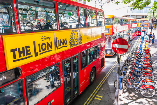 London, UK - June 22, 2018: Aerial high angle above view on street in Lodnon for signs ad for Disney Lion King on red bus by bicycle rack parking in summer