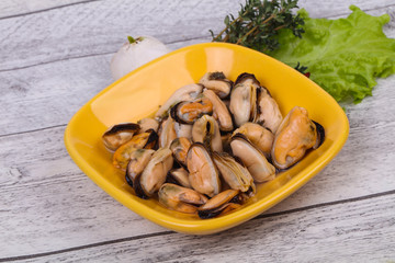 Pickled mussels in the bowl served pepper, garlic and salad