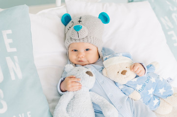 Little boy loves teddy bears. Baby in a teddy hat. Cute kid like Teddy Dear with toys.