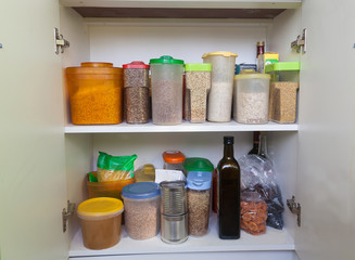 Groats, pasta, butter in a glass bottle, dried fruits, honey are on a shelf in the cabinet. Food. Stock. Warehouse. Epidemic.