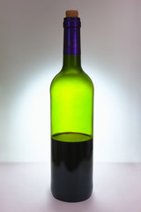A bottle of red wine, half empty. Of green glass. Soft focus