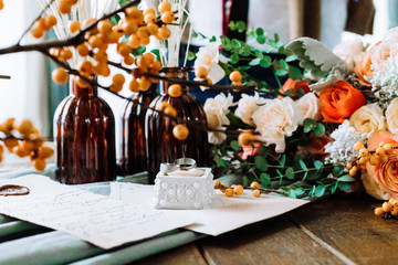 Wedding rings and decor in autumn vintage style close-up. Orange colors and romantic letter.