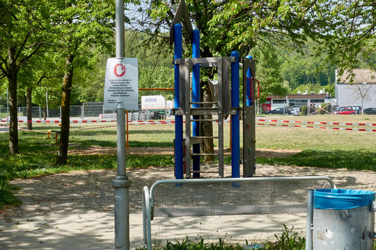 Menschen leerer Spielplatz in Deutschland, Ein Kletterturm f&uuml;r Kinder ist mit weis rotem Absperr Band umgeben. Im Vordergrund eine Bank und ein M&uuml;lleimer. Verbots Schild ist zu erkennen. 