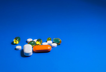 capsules, tablets and a syringe with a needle on a plain blue background. The concept COVID19
