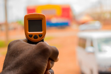 Close-up shot of a man ready to use infrared forehead thermometer (thermometer gun) to check body...