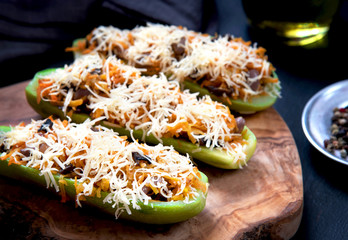 Vegetarian stuffed zucchini with vegetables and cheese on a wooden board