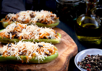 Stuffed zucchini with vegetables and cheese on a wooden board
