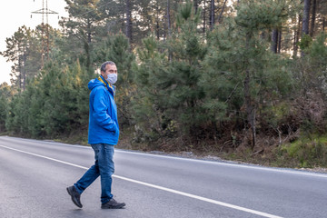 Man in protective mask walking on the rural wooded road. Covid-19 epidemic disease
