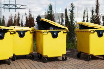 yellow trash bins with trash in black bags inside