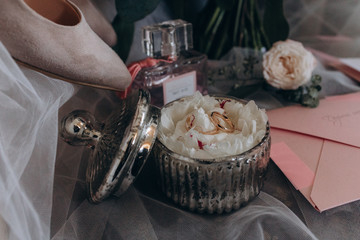 Wedding rings lie in a wooden box on a flower.