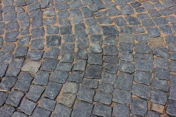 Brick cobblestone street pavement close-up background. Empty dark stone paved pattern on old town ancient street, abstract cobblestone paved road pattern