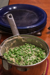 creamed peas in a pot set on the dining room table