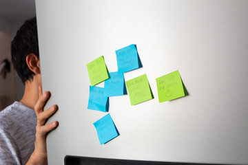 Man opening refrigerator door and showing reminders pasted on the other side