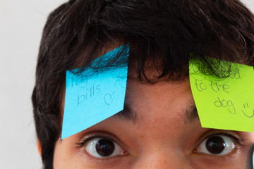 Young Hispanic man with a beard and glasses overwhelmed by reminders taped to his face