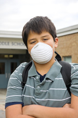 young boy with mask in front of school