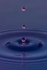Fotobehang Gotas de agua color azul con morado suspendidas en el aire y  formando ondas en la superficie liquida, que representan tranquilidad o serenidad © Edgar1 BJ