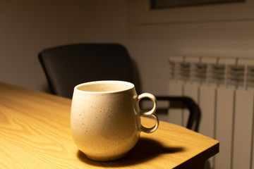 Taza sobre mesa de madera y silla de fondo