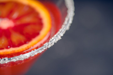 Red cocktail with bloody oranges in martini glass on the rustic background. Selective focus....