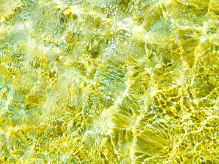 Transparent ripple water texture in a summer sea, ocean or swimming pool. Clear shiny textured surface under sunlight.