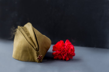 Window with rain drops. Forage,garisson cap of World War II soldier with red star,carnation...