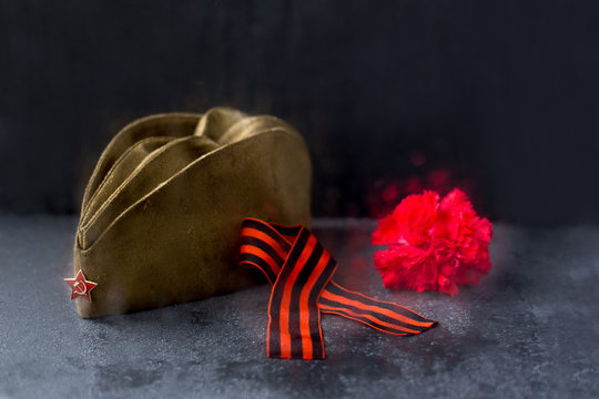 Window,rain drops.Forage,garisson cap of World War II soldier. Red star,carnation flower,St. George ribbon.May 9.Memory 75 years of victory day of Soviet Union in Great Patriotic War.Dark background
