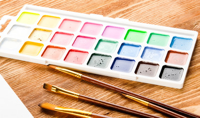 Brushes and paints on a wooden table. Creativity concept.