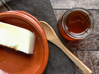 Dairy curd dessert, honey pot, wooden spoon on wooden table