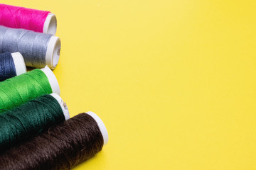 Coils with multicolored threads on yellow background