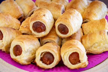 Pig-in-a-blanket pastries on pink paper plate, Johannesburg, South Africa