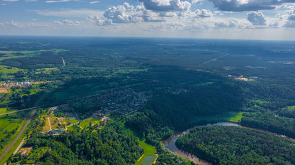 Panoramic aerial view photo from flying drone on beautiful forests of Sigulda, the meadows, and the flowing river Gauja. Sigulda, Latvia in summer (series)