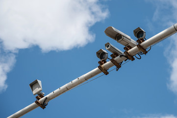 surveillance cameras and radars on a metal pole above the road. lights and security cameras