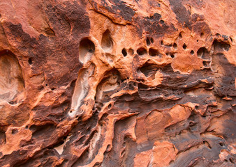 The textured surface of red stone with traces of wind and water.