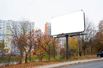Blank white billboard for advertisement in the roadside. Autumn day in the city