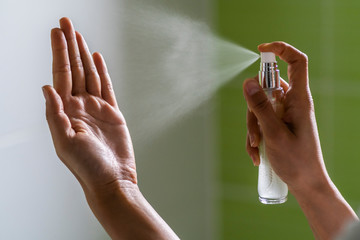 Caucasian woman wipes her hands with alcohol-based hand-washing spray as a preventive measure against coronavirus (Sars-CoV-2, Covid-19) virus infection. Hygienic antibacterial sanitizer hand gel.