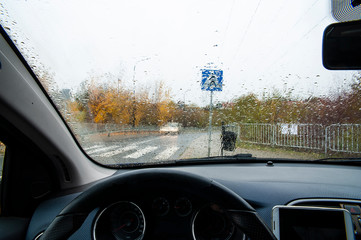 Road and blurred car viewed through the wet windshield